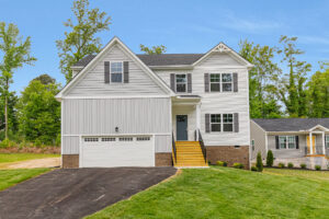Two-story white house with a double garage, yellow steps, and a paved driveway, surrounded by trees and grass.
