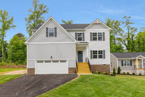 Two-story white house with a double garage, yellow steps, and a paved driveway, surrounded by trees and grass.