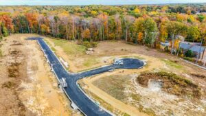 Aerial view of Poplar Villages paved road and cul-de-sac under construction, surrounded by colorful autumn trees.