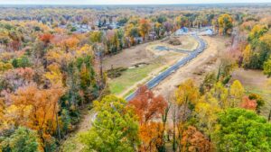 Aerial view of Poplar Village under construction, nestled among vibrant autumn trees.