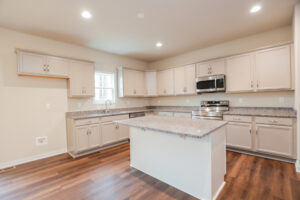 Spacious kitchen in Poplar Village with beige cabinets, granite countertops, center island, and stainless steel appliances.