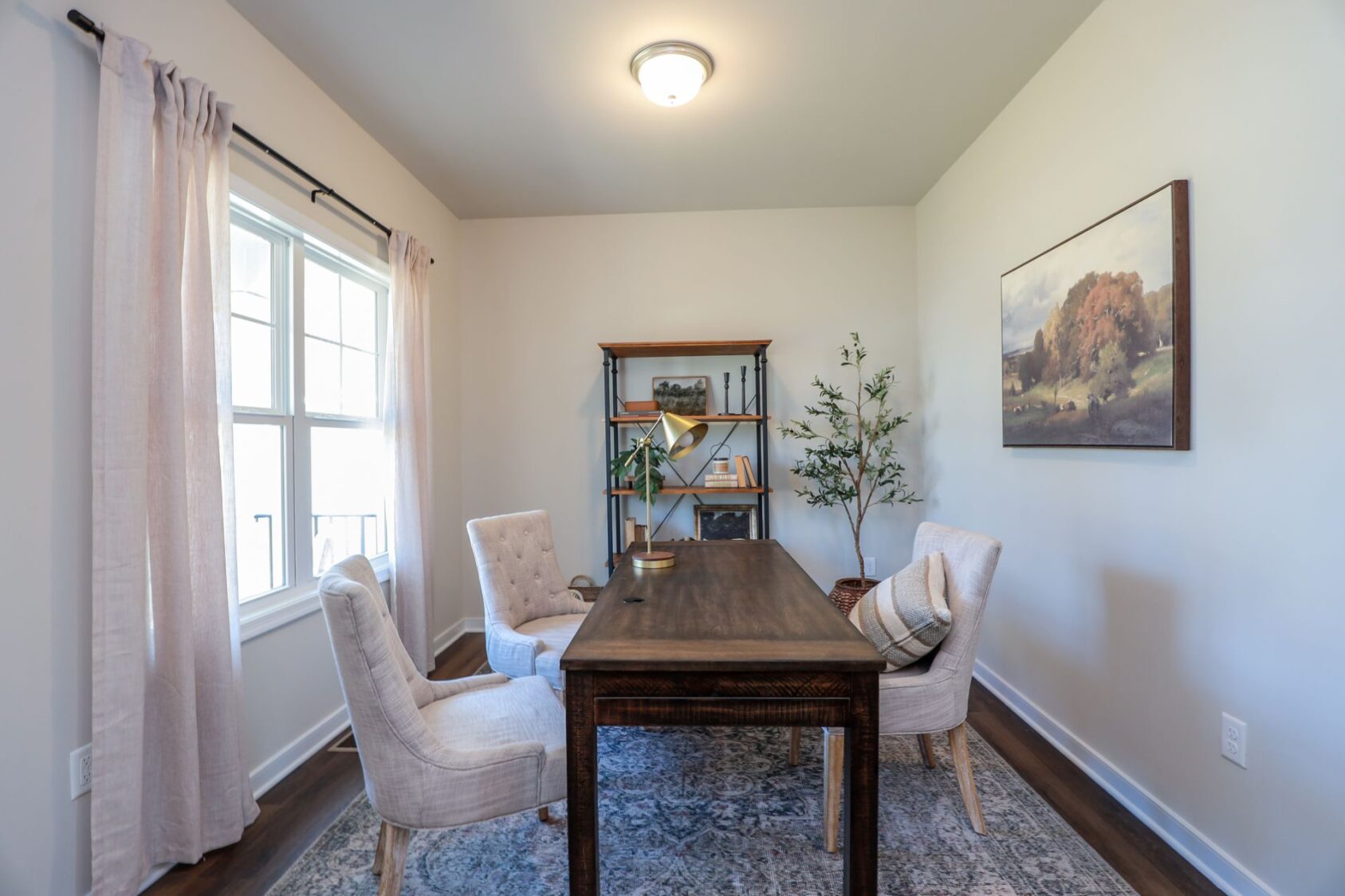 Bright home office in one of the new homes in Richmond VA, with two chairs, a wooden desk, shelves, and art on the wall.