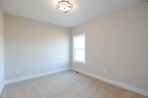 Empty room with beige carpet, light gray walls, a window, and a modern ceiling light fixture in Poplar Village.