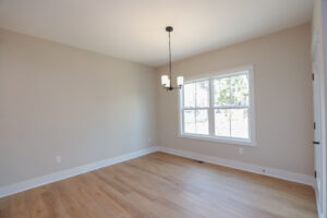 Empty room in Poplar Village with light wood flooring, beige walls, a window, and a ceiling light fixture.