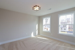 Empty room with beige carpet, two windows, and a geometric ceiling light fixture in Poplar Village.