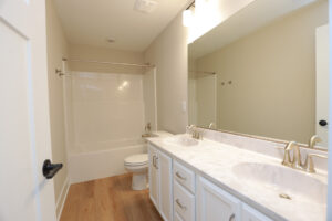 Modern bathroom at Poplar Village with a double sink vanity, marble countertop, and a bathtub with a shower curtain.