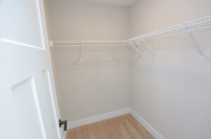 Empty walk-in closet in Lot 1, Poplar Village, with beige walls, carpeted floor, and white wire shelving.