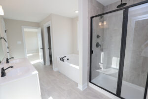 Modern bathroom in Poplar Village with a glass shower, bathtub, and double sink vanity in neutral tones.