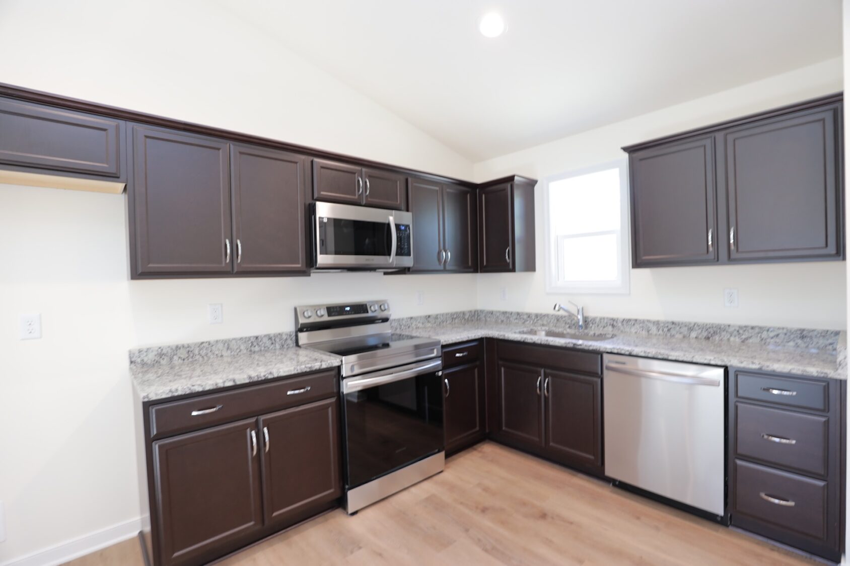 Modern kitchen with dark cabinets, stainless steel appliances, and granite countertops.