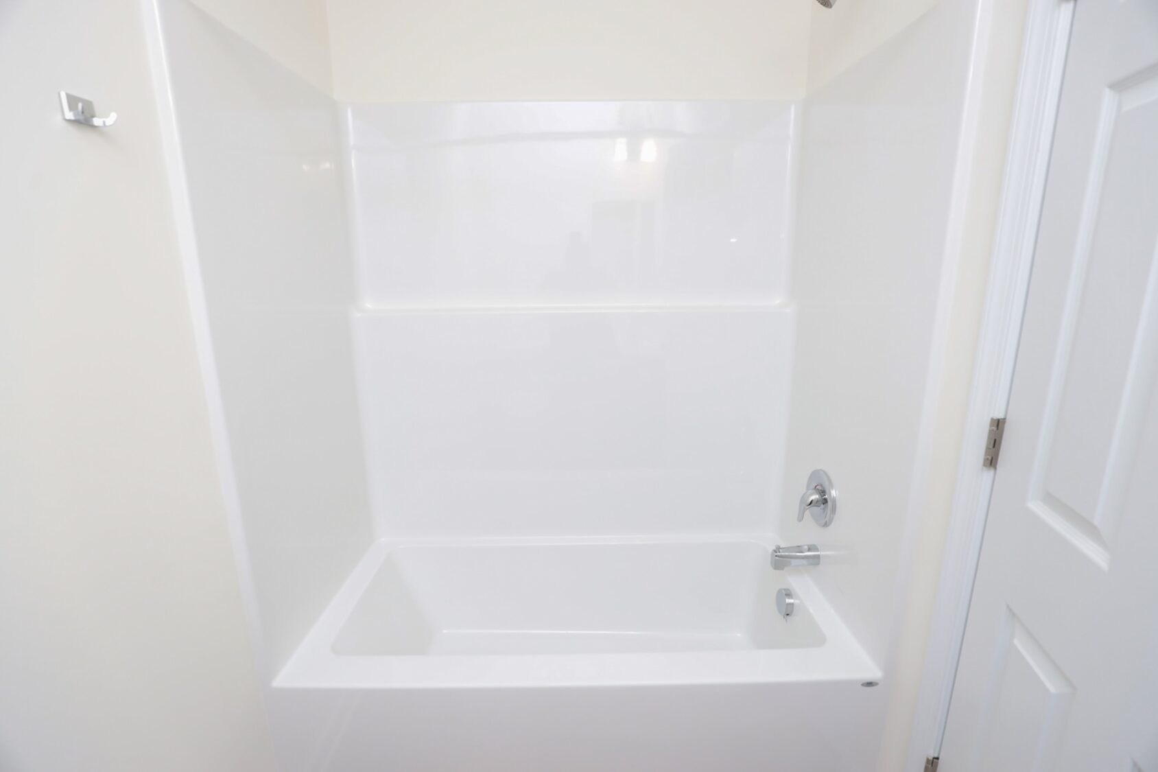 White bathtub with a showerhead, faucet, and soap holder in a clean, bright bathroom.