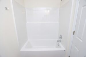 White bathtub with a showerhead, faucet, and soap holder in a clean, bright bathroom.
