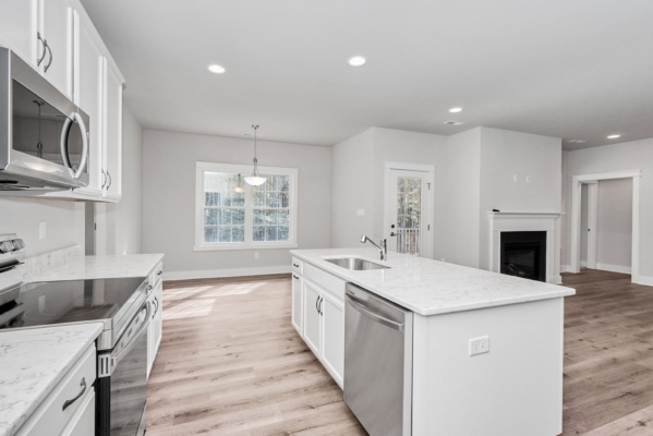 Modern kitchen with white cabinets, stainless steel appliances, and a central island. Bright with natural light.