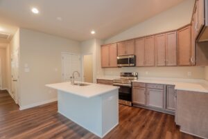 Modern kitchen with wood cabinets, stainless steel appliances, white island, and wood flooring.