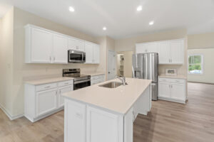 Modern kitchen in Patrick Henry Heights, featuring white cabinets, stainless appliances, and a central island with sink.