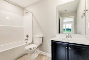 Modern bathroom with a white bathtub, toilet, and black vanity with double sinks and a large mirror.