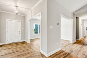 Bright entryway with light wood floors, white walls, and doorways leading to multiple rooms in a modern home.