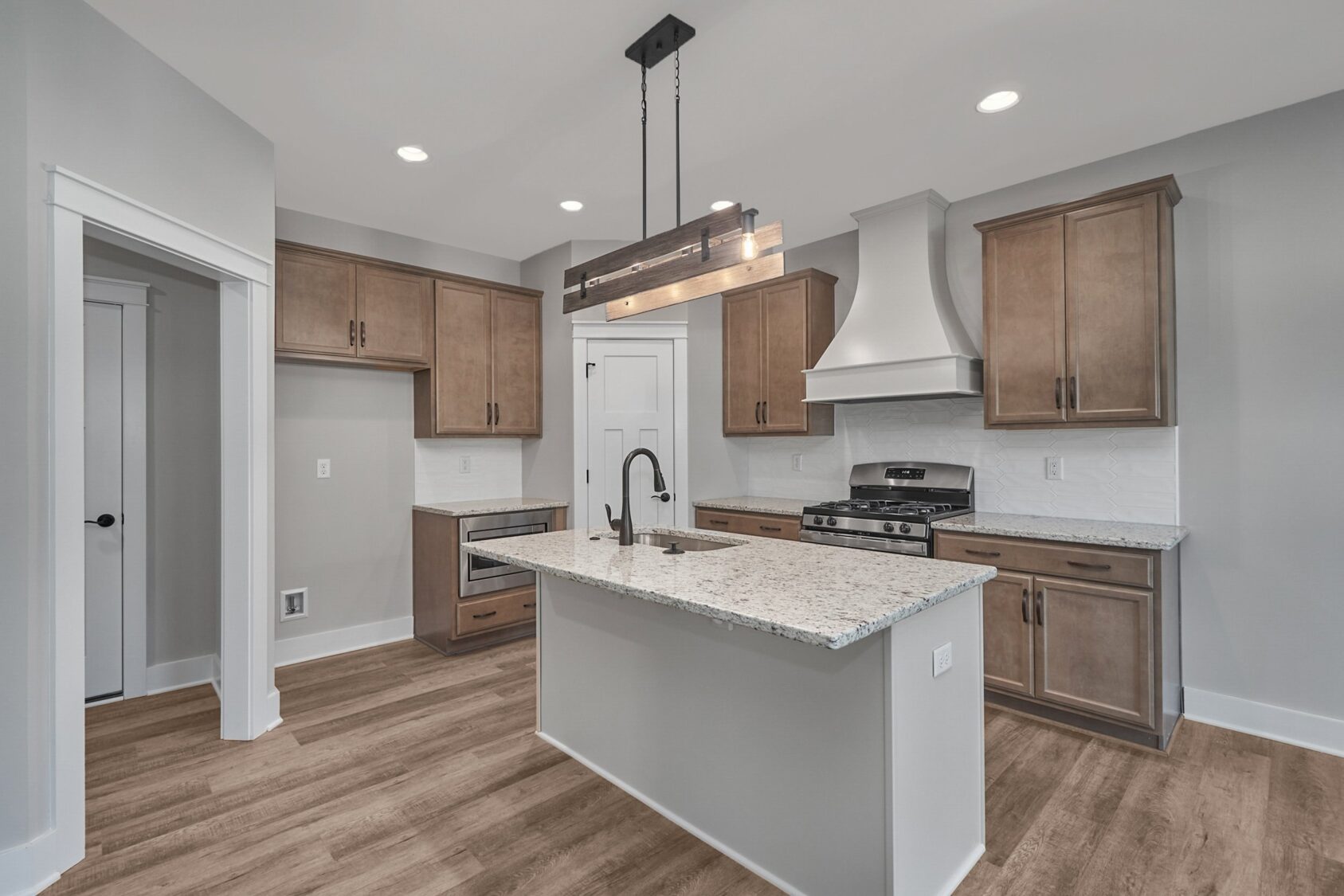 Modern kitchen at Shirley Commons with wood cabinets, center island, stainless steel appliances, and pendant lighting.