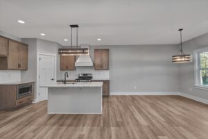 Modern kitchen with wood cabinets and dining area in the bright, open spaces at Shirley Commons senior living.