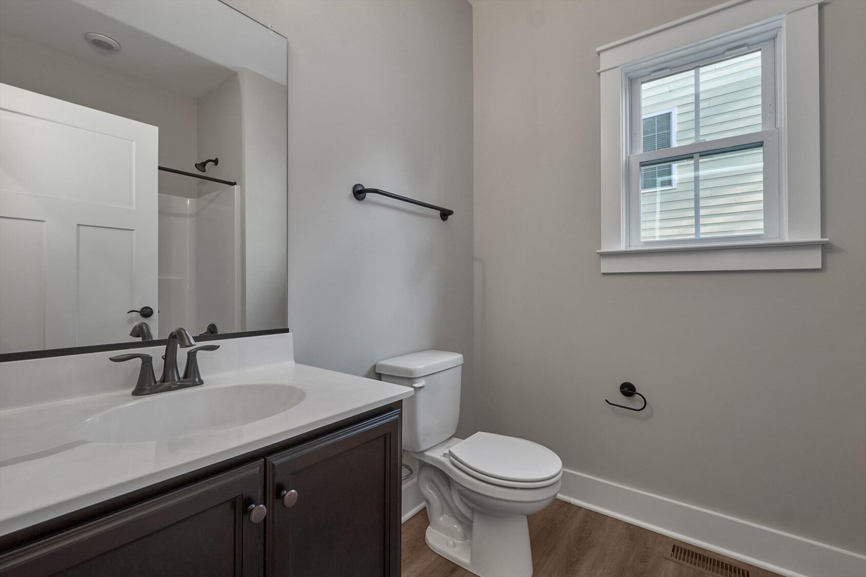 Modern Shirley Commons bathroom with a sink, dark wood vanity, toilet, window, and neutral-toned walls and floor.