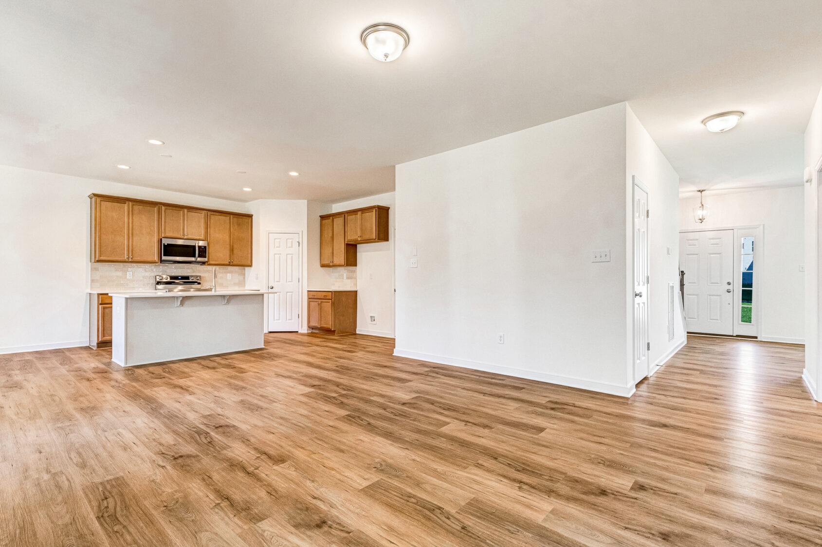 Open kitchen with wood cabinets and island at Lot 29 in Poplar Village, adjoining spacious living area.