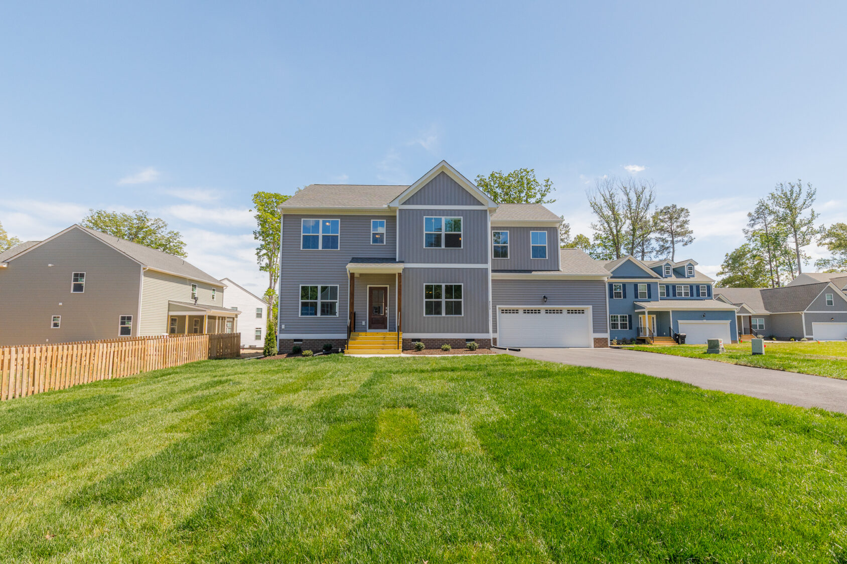 Two-story gray suburban house on Lot 28 in Poplar Village, featuring a front porch, green lawn, and driveway.