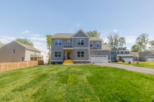 Two-story gray suburban house on Lot 28 in Poplar Village, featuring a front porch, green lawn, and driveway.