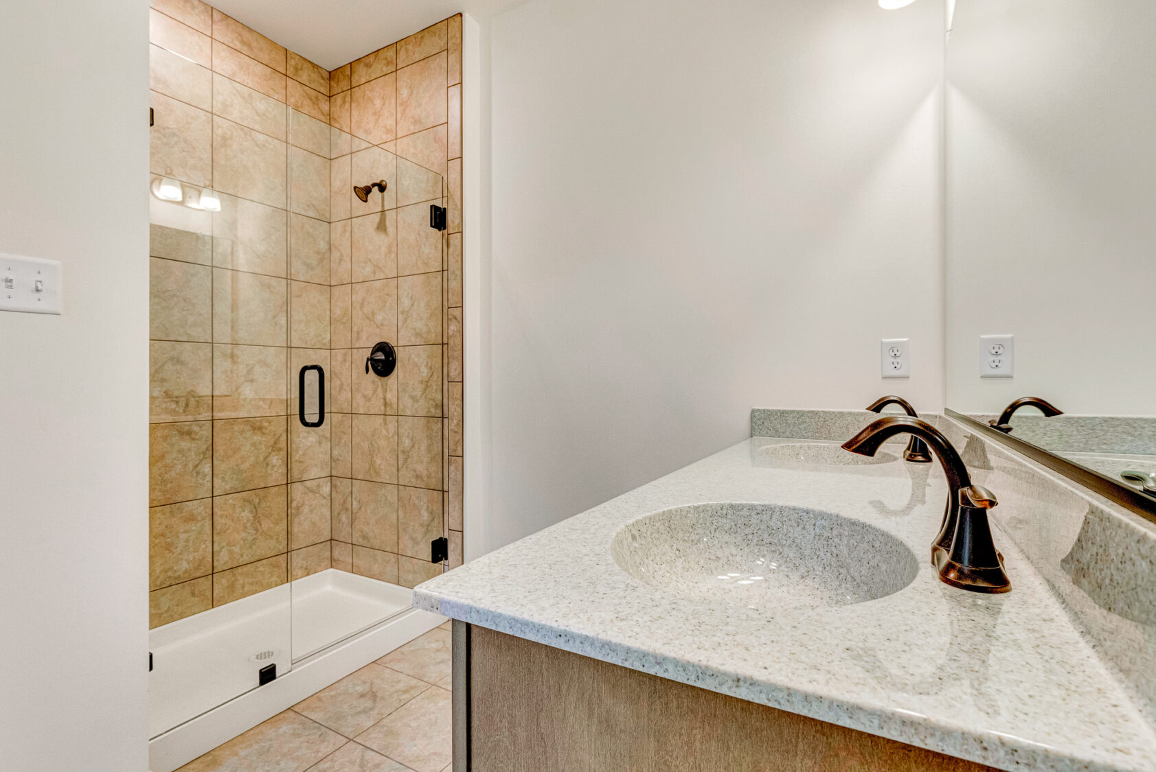 Bathroom at Somerset Hill with a tiled walk-in shower, glass door, and a double sink vanity with bronze fixtures—Kate style.