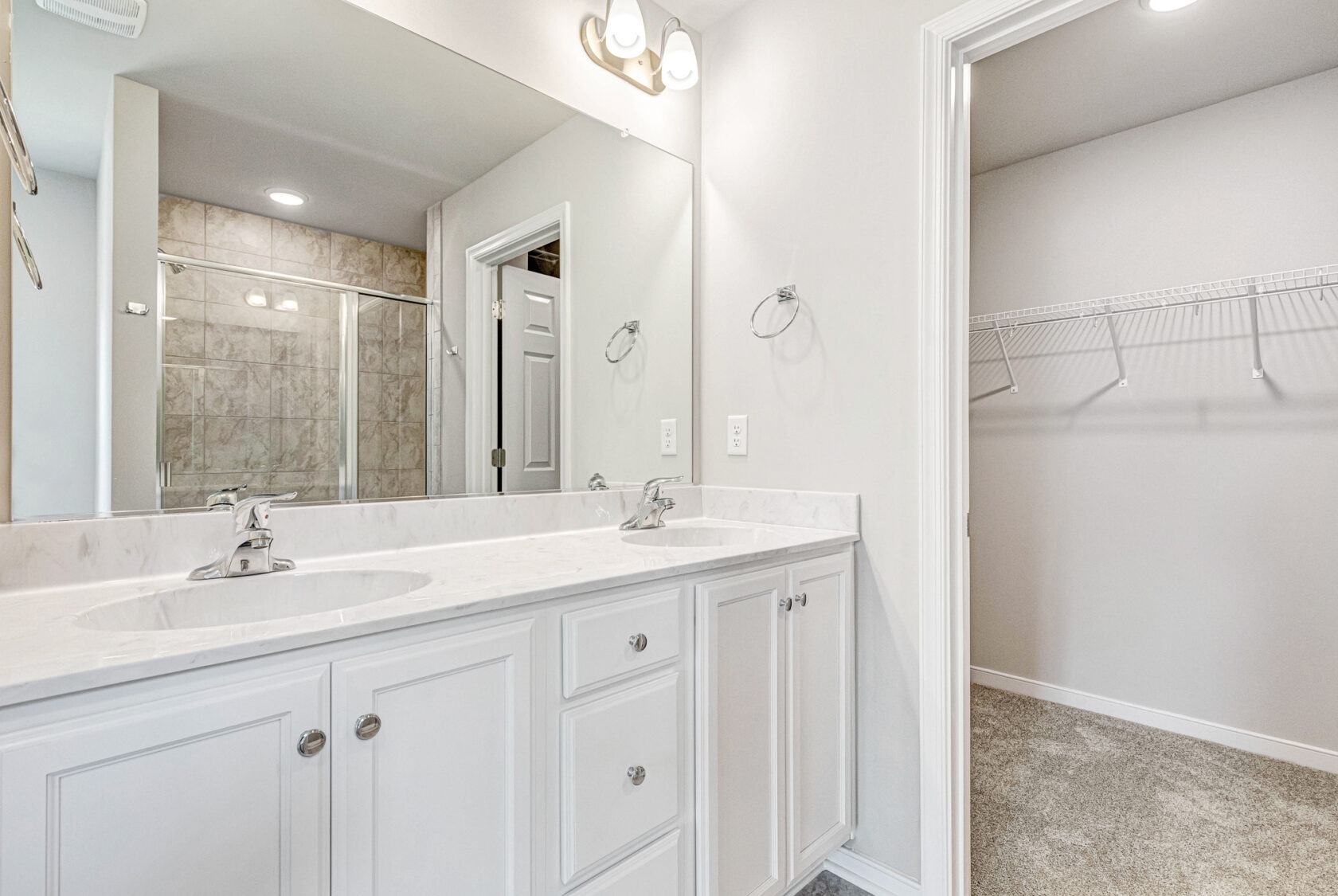 Modern bathroom in Lot 28, Poplar Village with double sink vanity, large mirror, and walk-in closet with wire shelving.