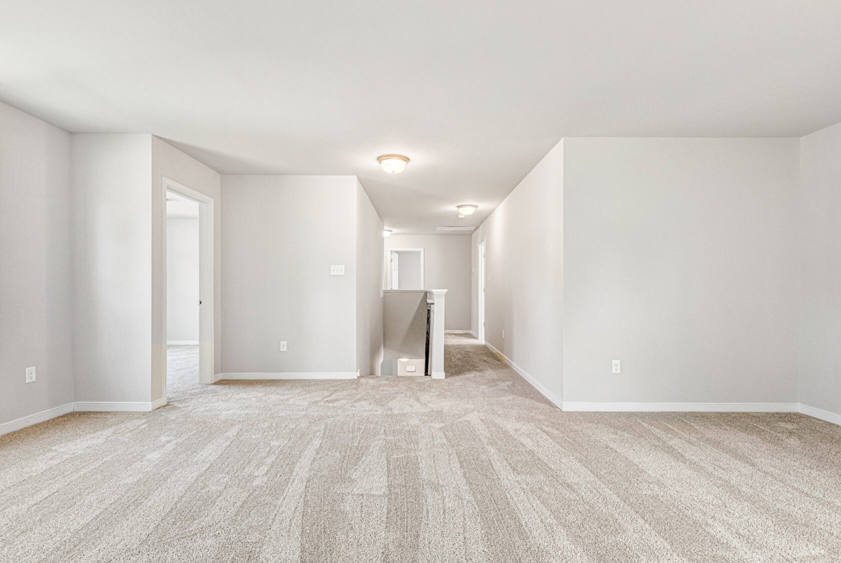 Spacious, carpeted upstairs hallway in Poplar Village Lot 28 with white walls and multiple doorways to other rooms.