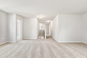 Spacious, carpeted upstairs hallway in Poplar Village Lot 28 with white walls and multiple doorways to other rooms.