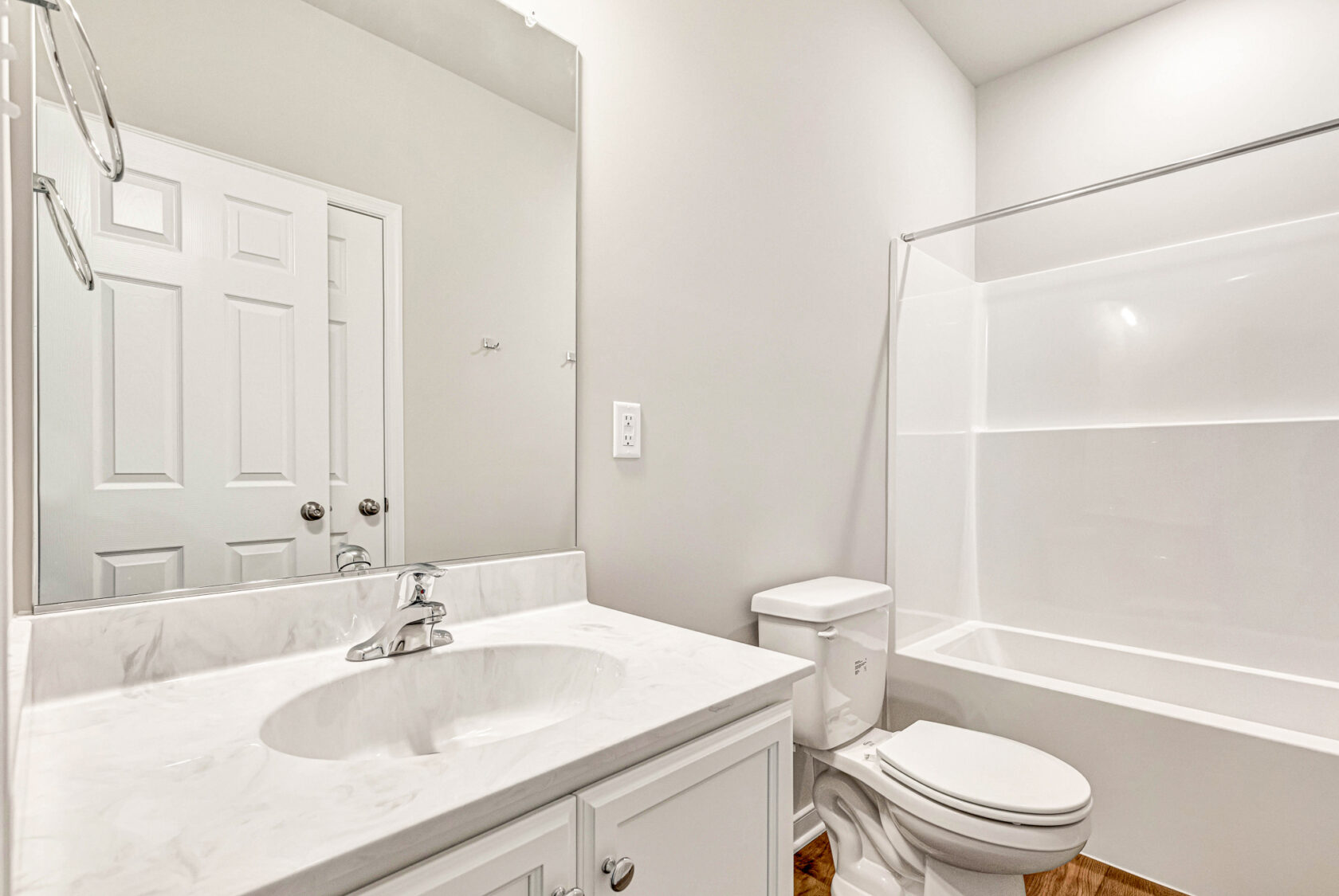 Bright, clean bathroom in Poplar Village Lot 28 with white vanity, sink, toilet, and bathtub.