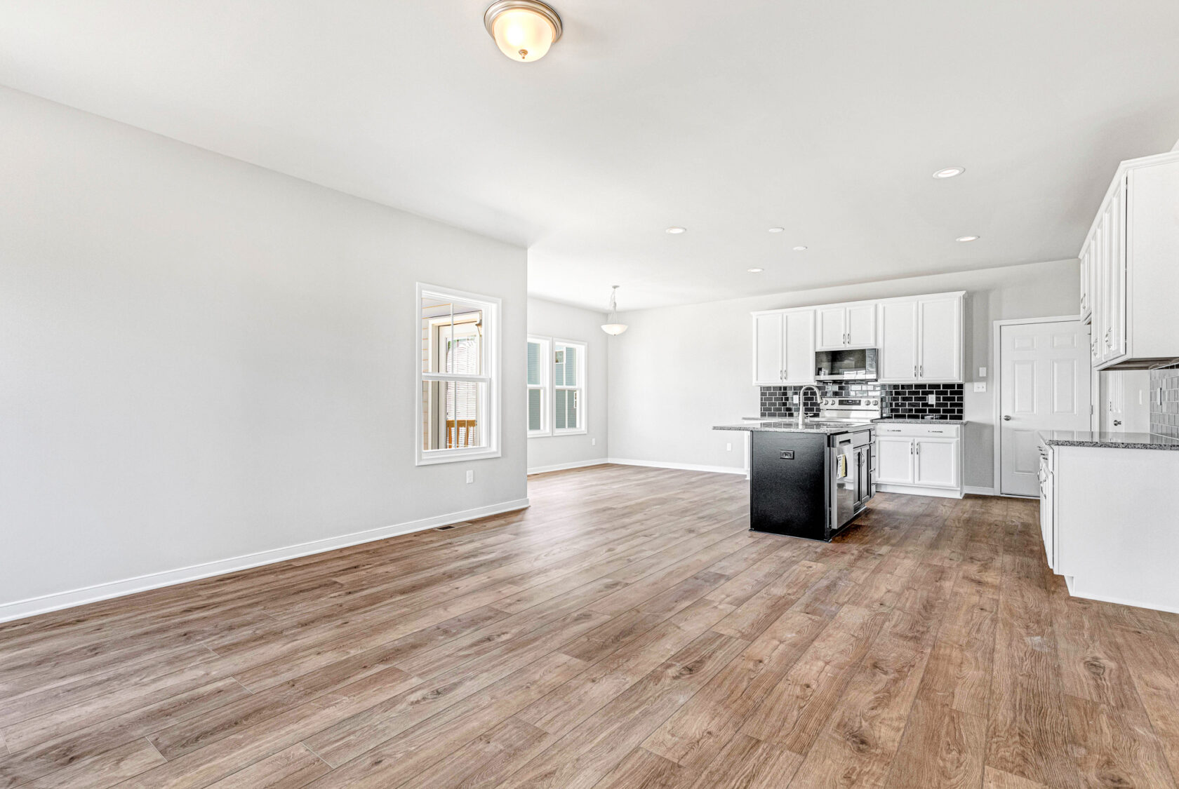 Bright, modern kitchen in Poplar Village with white cabinets, black island, and wood flooring in an open-concept space.