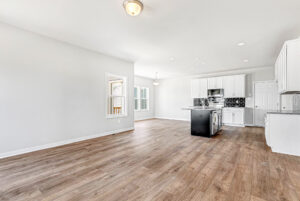 Bright, modern kitchen in Poplar Village with white cabinets, black island, and wood flooring in an open-concept space.