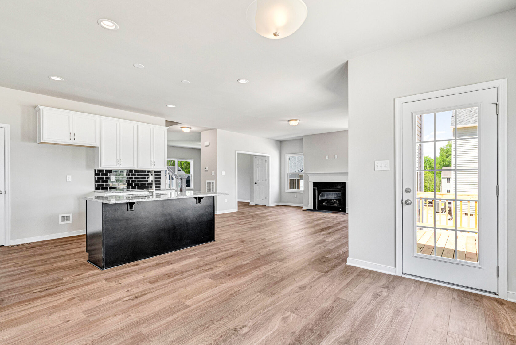 Bright modern kitchen in Lot 28, Poplar Village, with wood floors, black island, and glass door to deck.