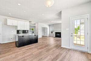 Bright modern kitchen in Lot 28, Poplar Village, with wood floors, black island, and glass door to deck.