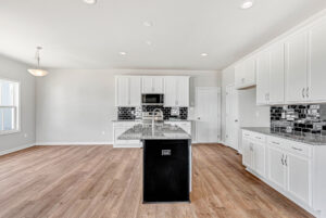 Modern kitchen in Poplar Village, Lot 28—white cabinets, black island, granite counters, and black tile backsplash.