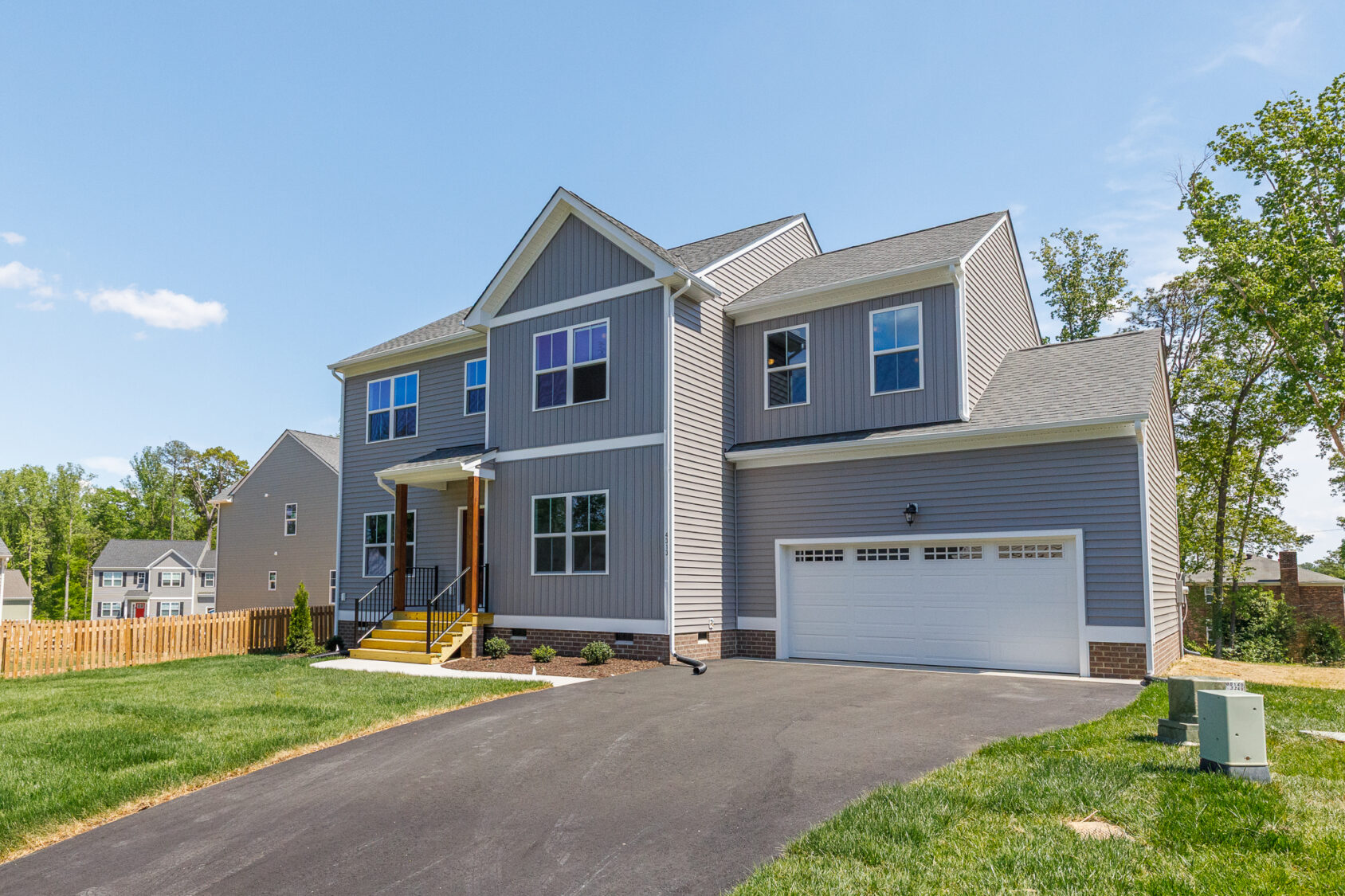 Two-story gray home in Poplar Village with front porch, attached garage, and driveway. Welcome to Lot 28!