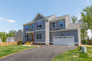 Two-story gray home in Poplar Village with front porch, attached garage, and driveway. Welcome to Lot 28!