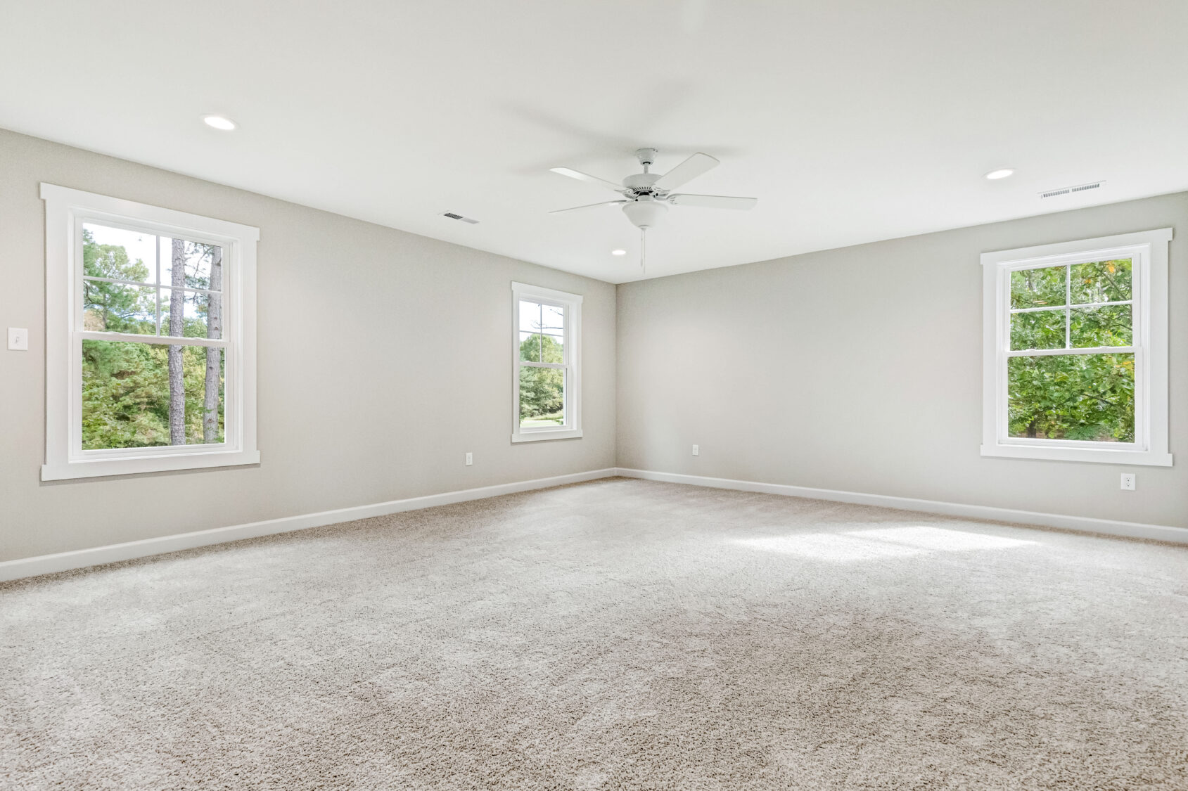 Spacious, empty Somerset Hill room with beige carpet, two windows, ceiling fan, and recessed lighting.