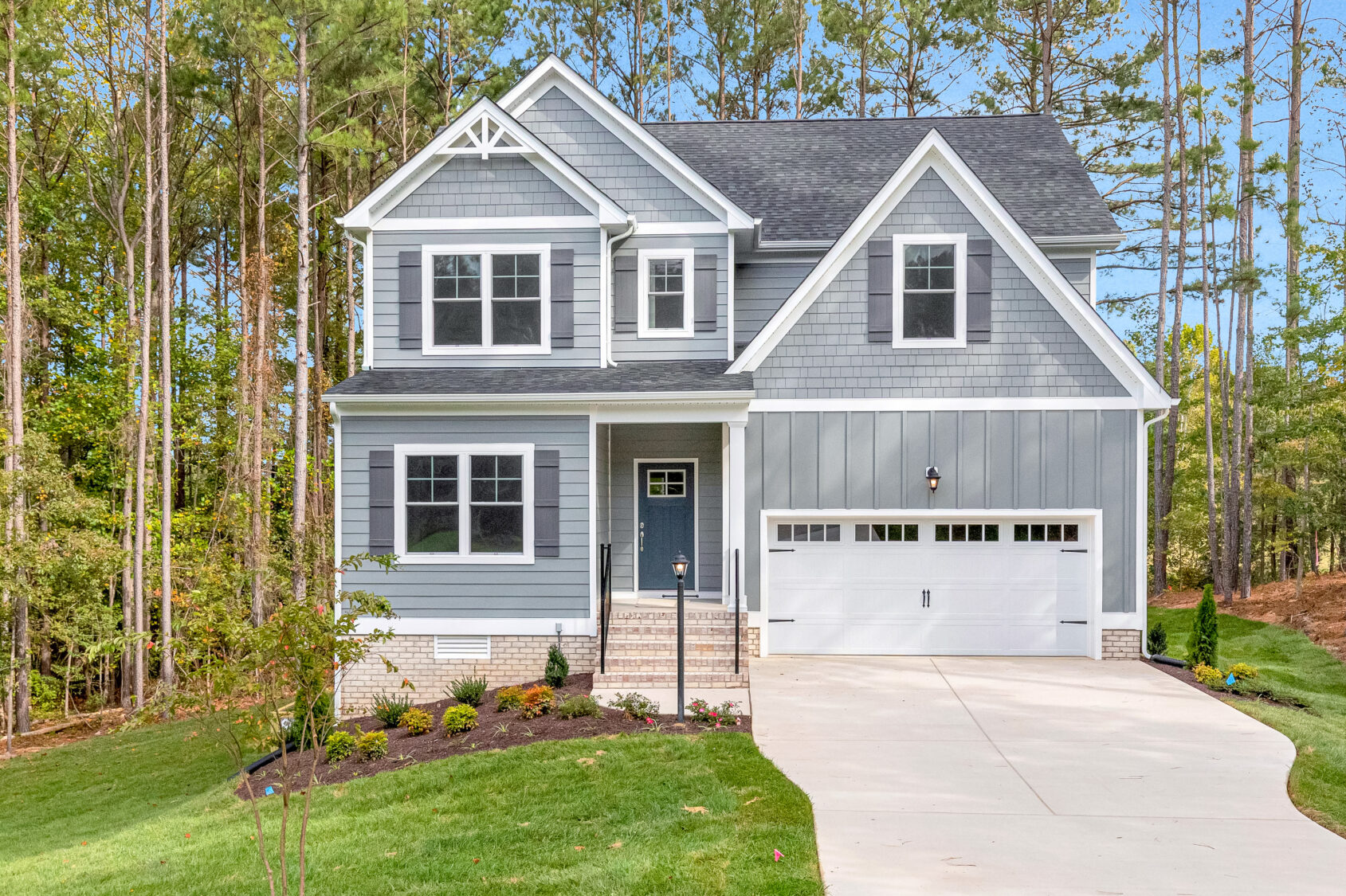 Two-story gray home on Lot 10, Somerset Hill, with white trim, front porch, garage, trees, and lush lawn.