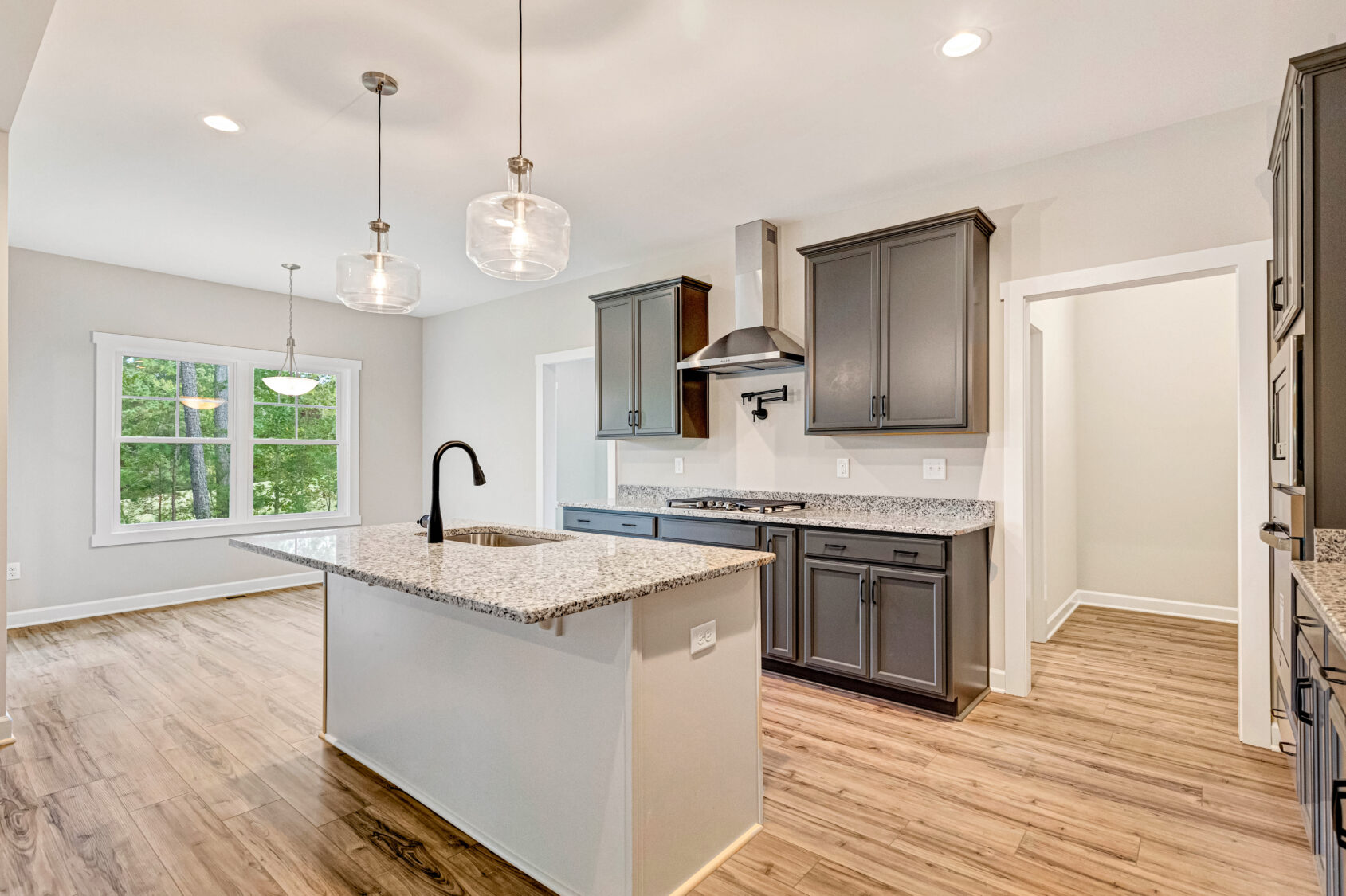 Modern kitchen in Lot 10, Somerset Hill, with gray cabinets, granite countertops, island, and wood flooring.