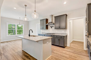 Modern kitchen in Lot 10, Somerset Hill, with gray cabinets, granite countertops, island, and wood flooring.