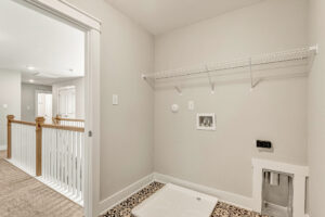 Lot 7 Somerset Hill: Empty laundry room with wire shelf, washer hookup, pet door, patterned tile, and beige walls.