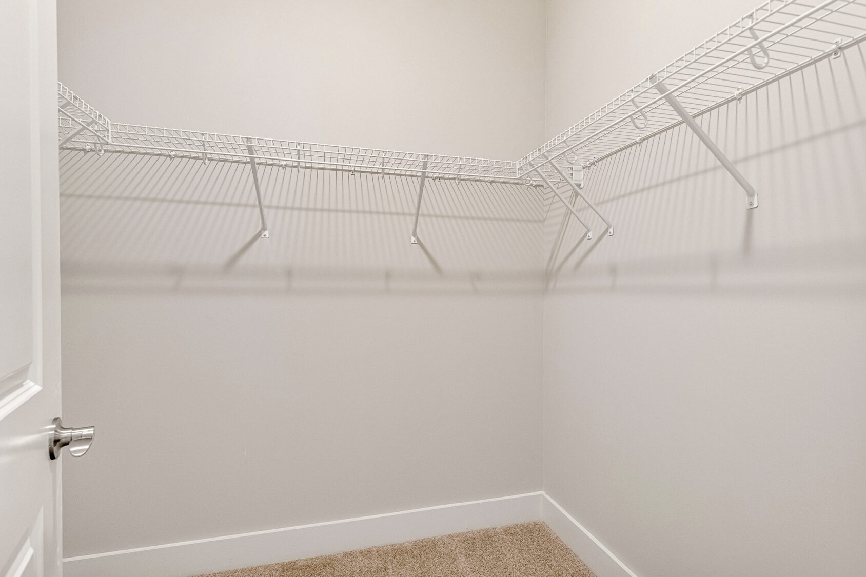 Empty walk-in closet in Lot 7, Somerset Hill; beige carpet, white walls, white wire shelves along two sides.