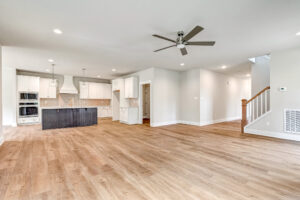 Spacious open-concept living area at Lot 20 Somerset Hill with wood floors, white kitchen, island, ceiling fan, and stairs.