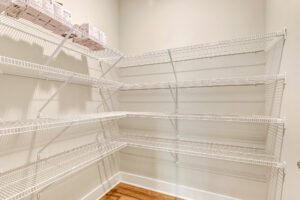 Lot 20 Somerset Hill: Empty pantry with white wire shelves, beige walls, wood floor, and boxes on the top left shelf.