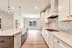 Modern kitchen in Lot 20, Somerset Hill with white cabinets, pendant lights, and a large window overlooking the yard.