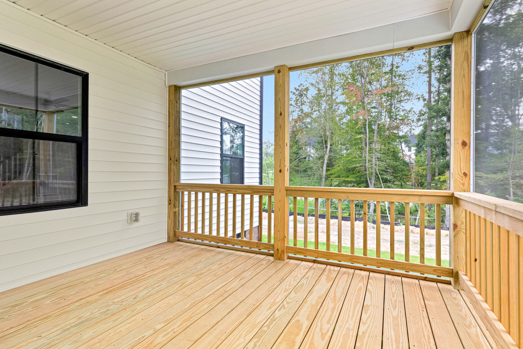 A covered wooden porch with railings on Somerset Hill, overlooking a grassy yard and trees in the background.